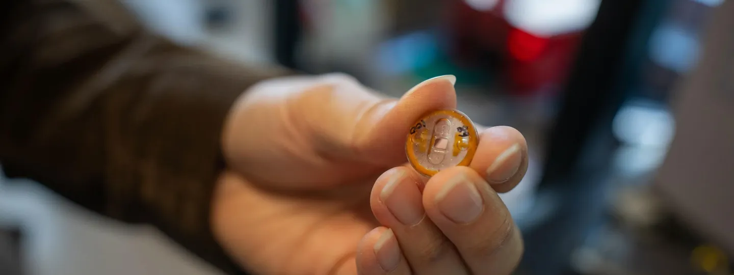 A person holds a button containing a tiny Penderia Technologies sensor. 