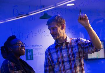 Kurt Langworthy shows a colleague an equation on a dry erase board.